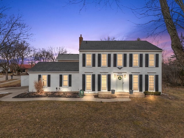 colonial house featuring roof with shingles and a chimney