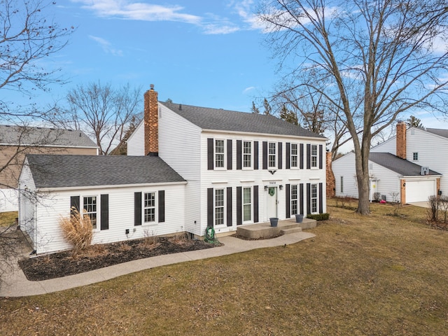 colonial home featuring a front lawn, a chimney, and a shingled roof