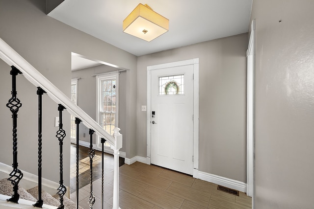 entrance foyer featuring visible vents, stairway, and baseboards