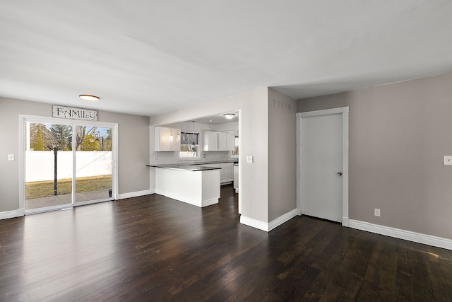 unfurnished living room featuring dark wood-style flooring and baseboards