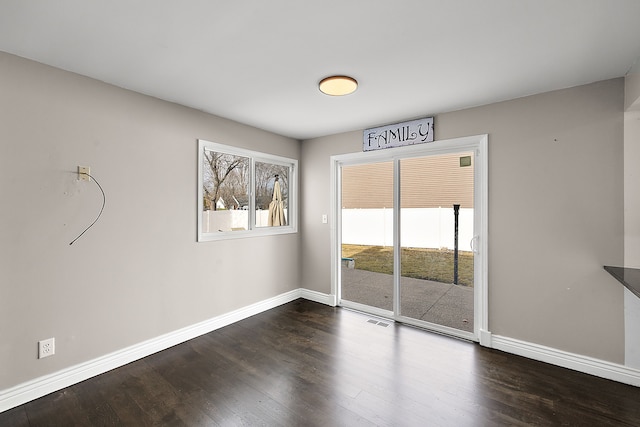 unfurnished room with dark wood-style floors, visible vents, and baseboards