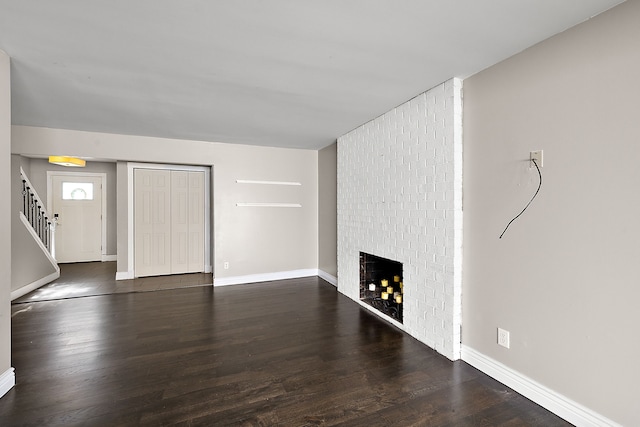 unfurnished living room featuring stairs, a fireplace, wood finished floors, and baseboards