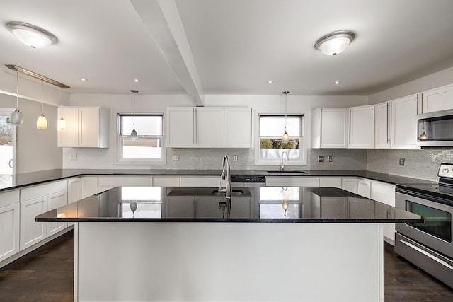 kitchen featuring appliances with stainless steel finishes, a sink, white cabinetry, and a healthy amount of sunlight