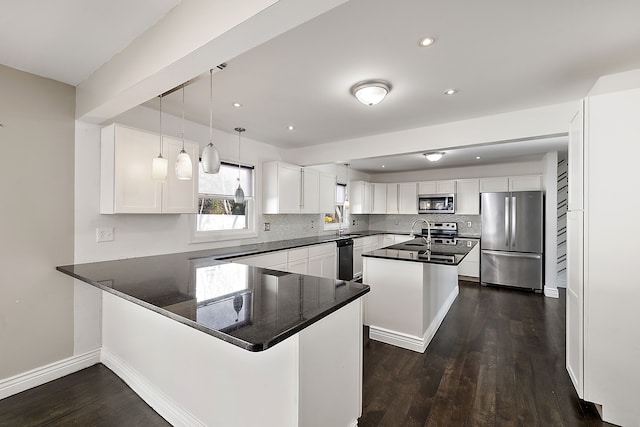 kitchen with decorative backsplash, white cabinets, appliances with stainless steel finishes, dark wood-style flooring, and a peninsula