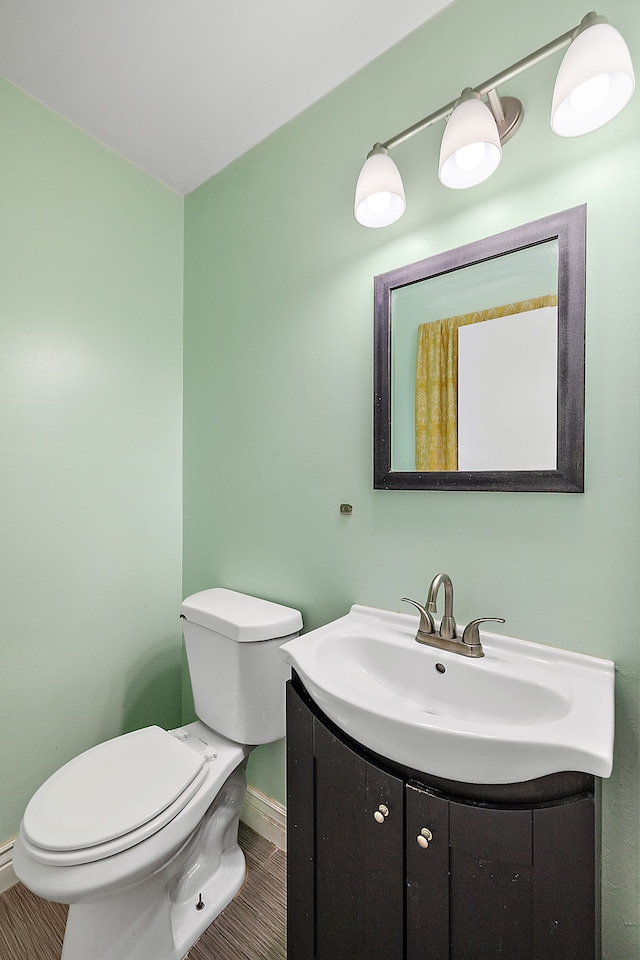 half bath featuring vanity, toilet, and baseboards