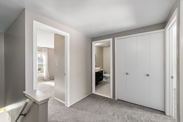 unfurnished bedroom featuring a closet, carpet, and ensuite bath