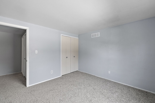 unfurnished bedroom featuring carpet floors, baseboards, visible vents, and a closet