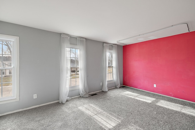 unfurnished room featuring carpet, visible vents, and baseboards