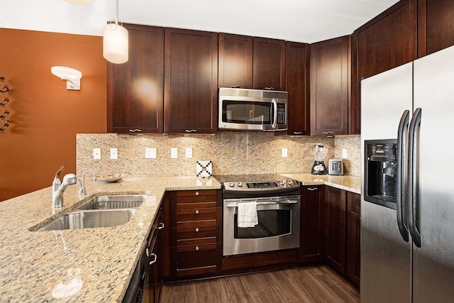 kitchen featuring sink, light stone counters, tasteful backsplash, decorative light fixtures, and appliances with stainless steel finishes