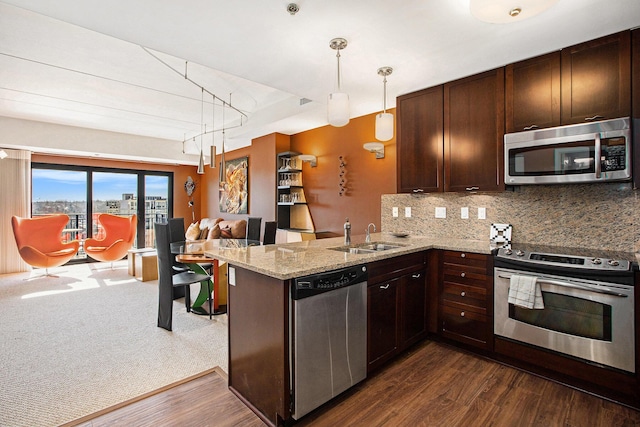 kitchen featuring sink, tasteful backsplash, appliances with stainless steel finishes, kitchen peninsula, and pendant lighting