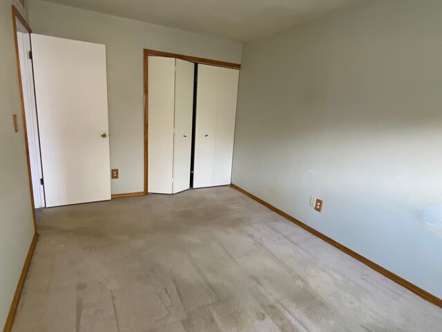 unfurnished bedroom featuring light colored carpet and a closet