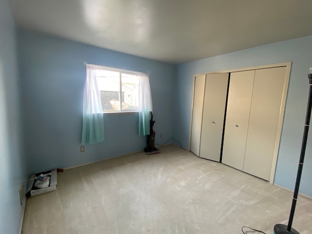 unfurnished bedroom featuring light colored carpet and a closet