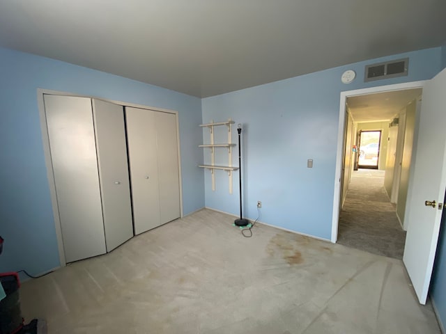 unfurnished bedroom featuring light colored carpet and a closet