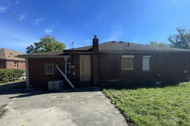 rear view of property featuring cooling unit and a lawn