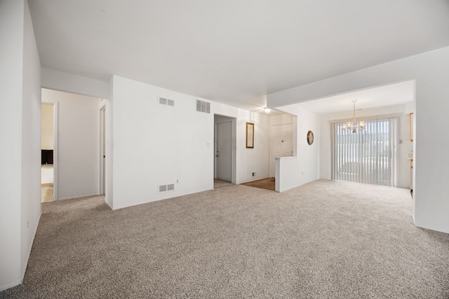 unfurnished living room featuring light colored carpet and an inviting chandelier