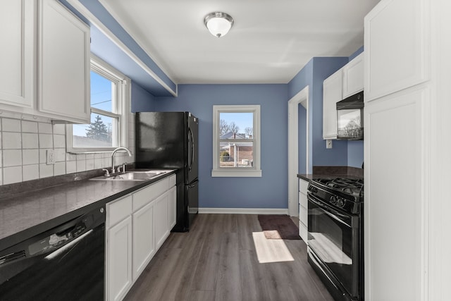 kitchen with dark countertops, backsplash, a healthy amount of sunlight, black appliances, and a sink