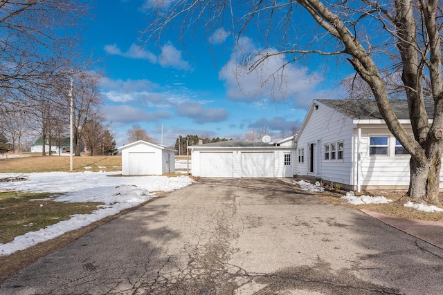 snow covered property with a garage and an outdoor structure