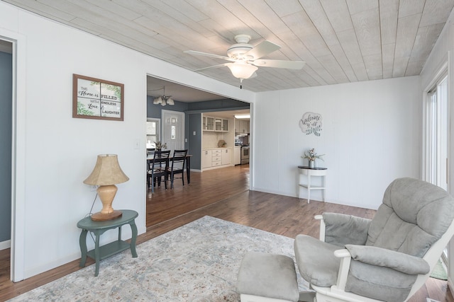 living area featuring dark hardwood / wood-style floors, wooden ceiling, and ceiling fan