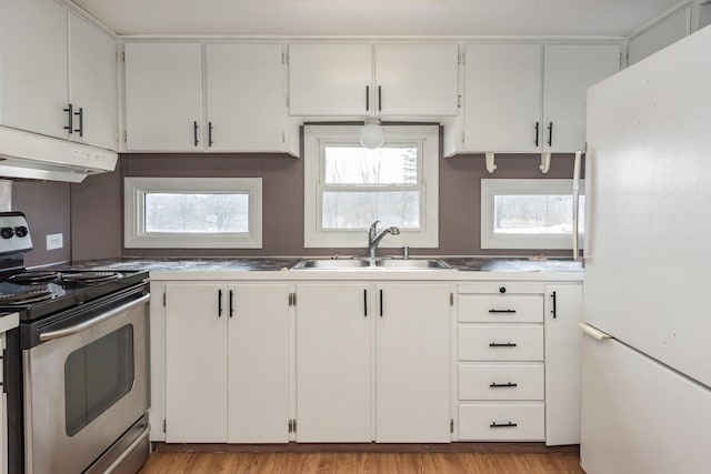 kitchen with white fridge, white cabinetry, stainless steel counters, and stainless steel range with electric cooktop