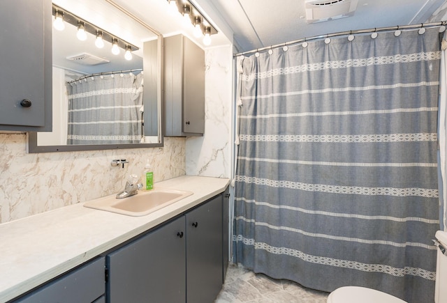 bathroom with vanity, decorative backsplash, and toilet