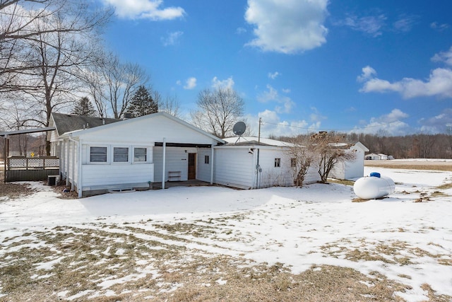 snow covered back of property featuring central AC