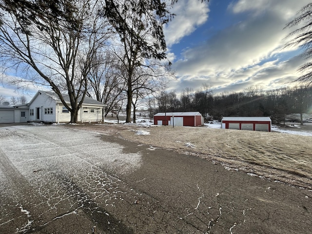 yard layered in snow with a garage and an outbuilding