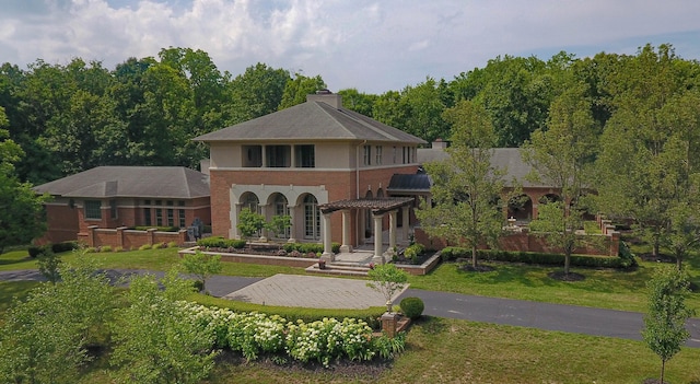 back of house featuring a chimney, brick siding, and a yard