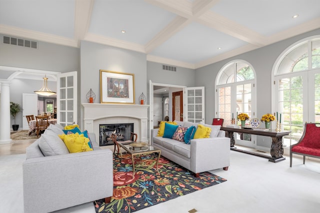 carpeted living area featuring coffered ceiling, a glass covered fireplace, visible vents, and ornate columns