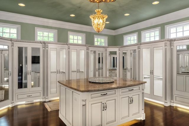 spacious closet with a high ceiling, dark wood-style floors, and an inviting chandelier