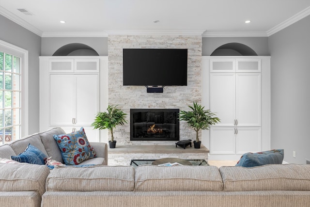 living room featuring recessed lighting, a stone fireplace, visible vents, and ornamental molding
