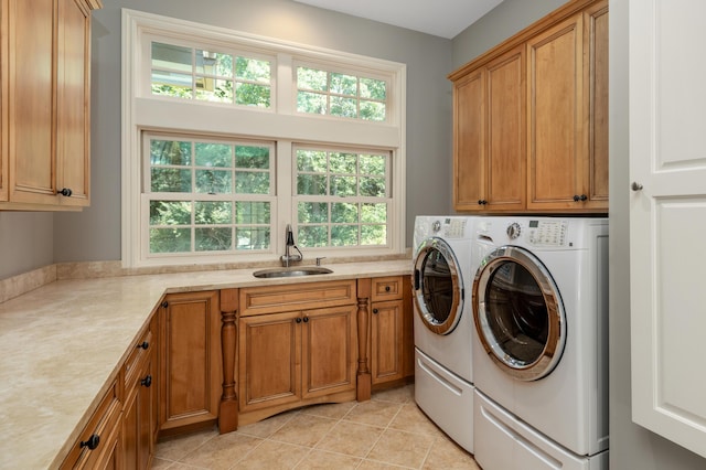 washroom featuring washing machine and dryer, light tile patterned flooring, a sink, and cabinet space
