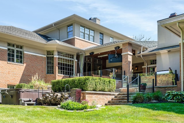 rear view of property featuring brick siding, a yard, a chimney, and stucco siding