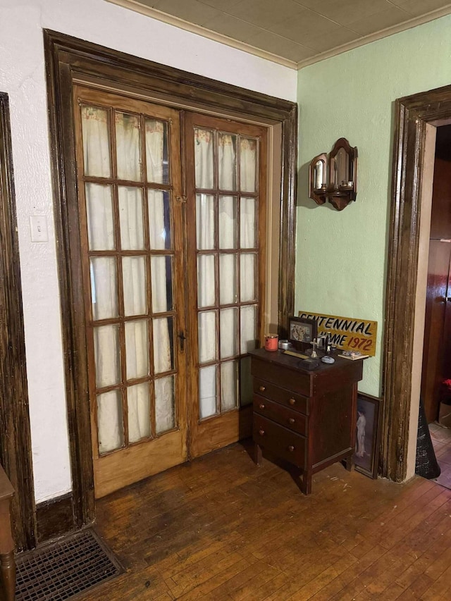 doorway featuring a textured wall, ornamental molding, dark wood-type flooring, and french doors