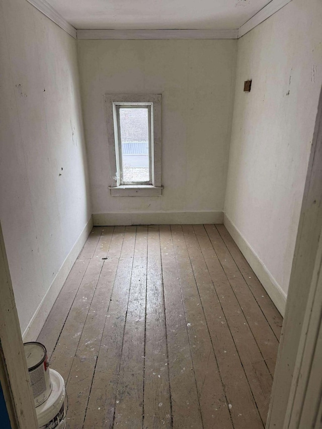 spare room featuring baseboards, crown molding, and hardwood / wood-style floors