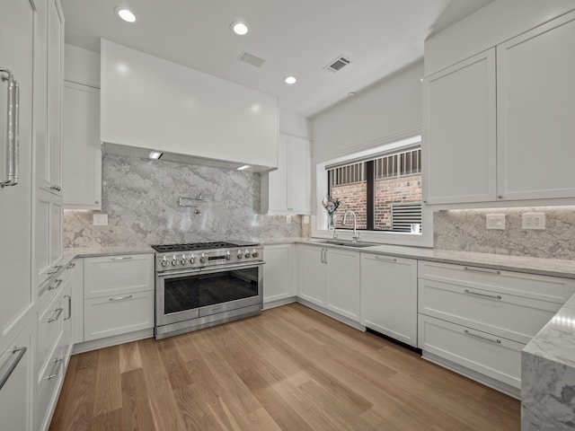 kitchen with sink, light hardwood / wood-style flooring, dishwasher, white cabinetry, and range with two ovens