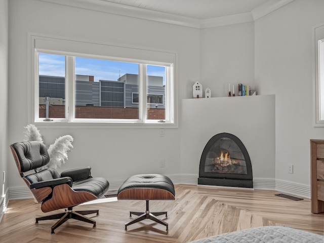 sitting room with ornamental molding and light hardwood / wood-style flooring