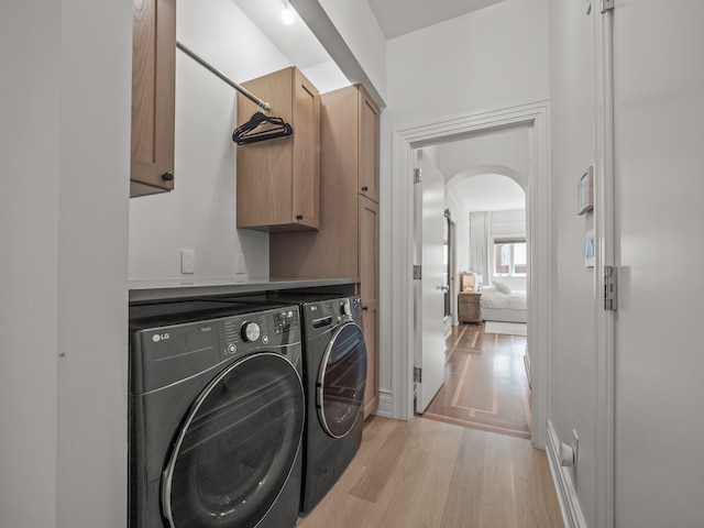 laundry room with cabinets, light hardwood / wood-style floors, and washing machine and clothes dryer