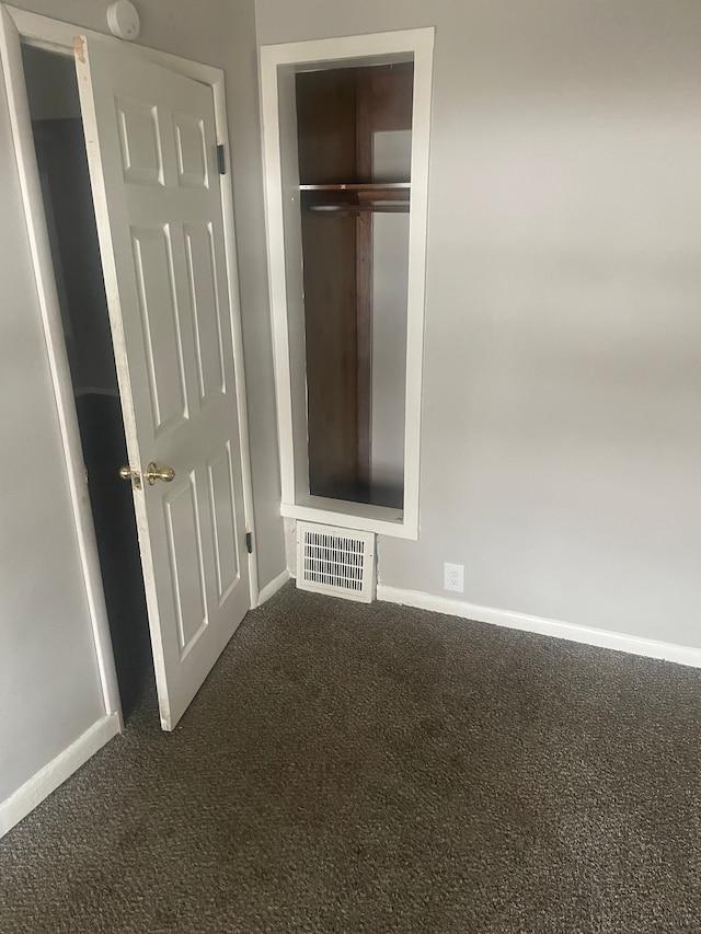 unfurnished bedroom featuring dark carpet and a closet