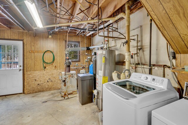 laundry room featuring laundry area, water heater, wooden walls, and washing machine and clothes dryer