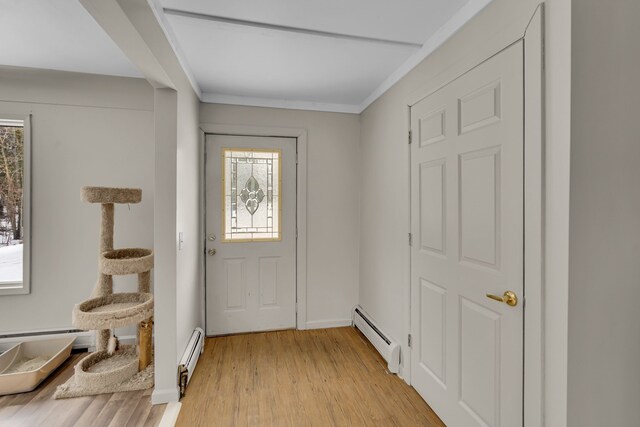 entryway featuring light wood-type flooring, ornamental molding, a baseboard radiator, and baseboards