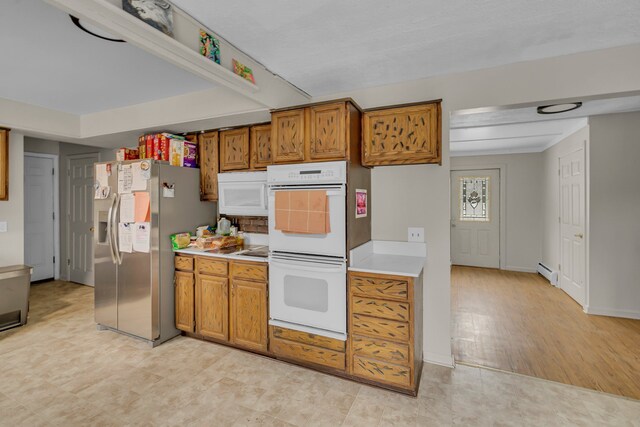 kitchen with light countertops, white appliances, baseboard heating, and brown cabinets