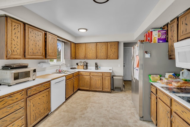 kitchen with light countertops, white appliances, a sink, and brown cabinets