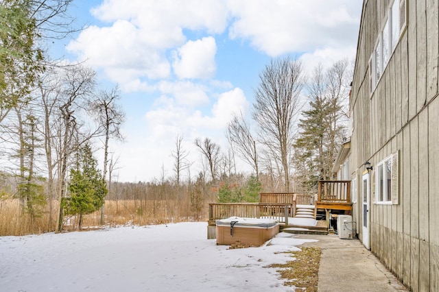 snowy yard with a deck and a hot tub