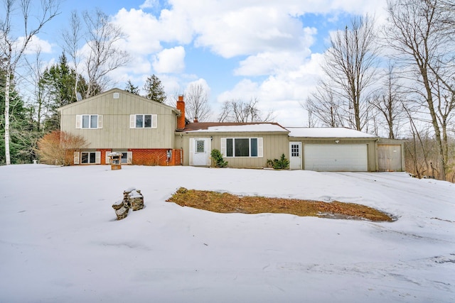 split level home with a garage, a chimney, and brick siding