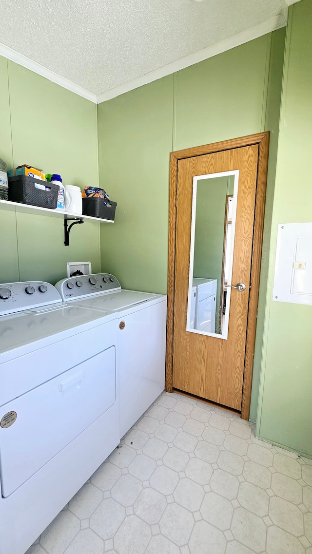 clothes washing area featuring ornamental molding, washing machine and dryer, and a textured ceiling