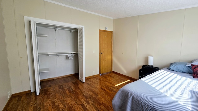 bedroom with ornamental molding, a textured ceiling, dark hardwood / wood-style flooring, and a closet