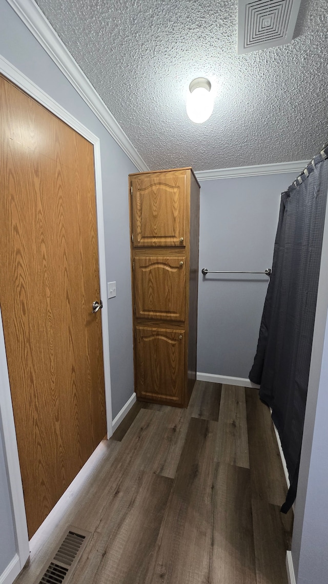 hallway with crown molding, dark wood-type flooring, and a textured ceiling