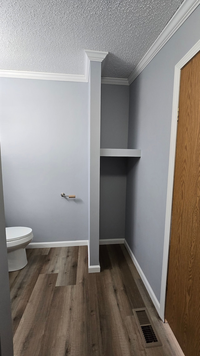 bathroom with ornamental molding, toilet, hardwood / wood-style floors, and a textured ceiling