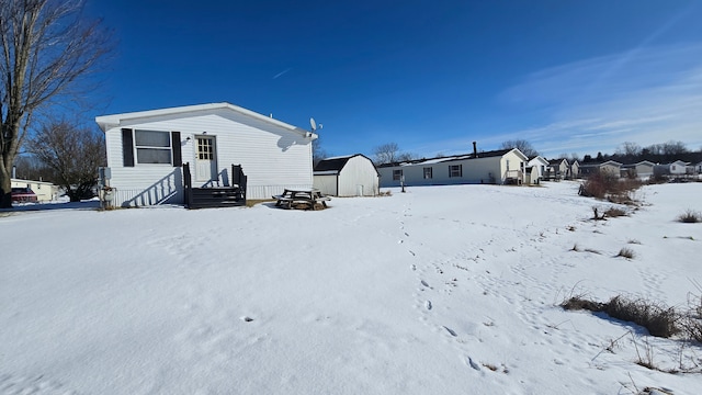 snow covered rear of property featuring a shed