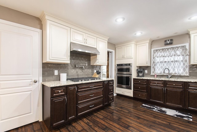 kitchen featuring appliances with stainless steel finishes, sink, backsplash, dark hardwood / wood-style flooring, and dark brown cabinetry